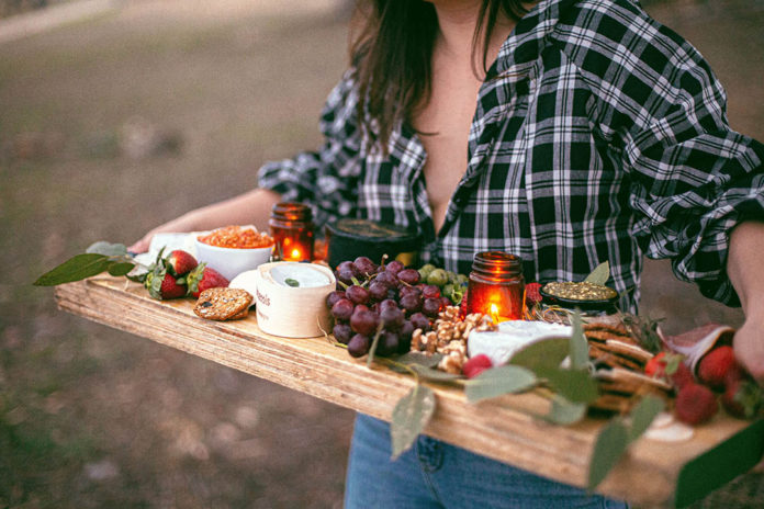 Woman carrying a wooden board of cheese and snacks