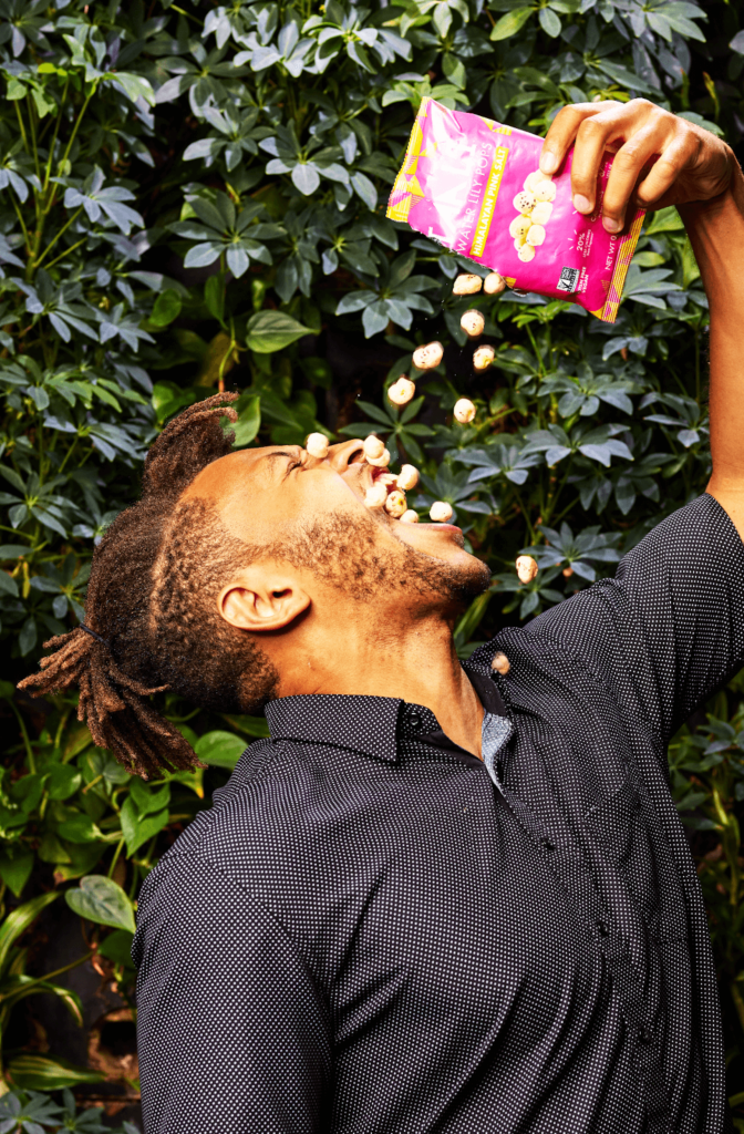 A snacker enthusiastically pours popcorn into his mouth.